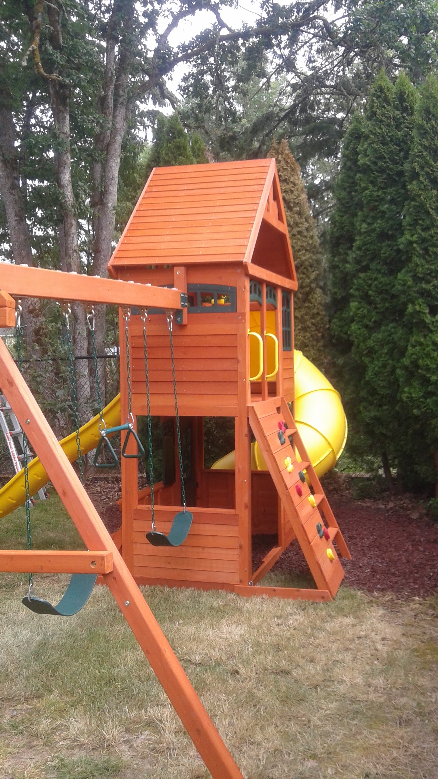 Wooden swing set and playhouse fully assembled in a backyard